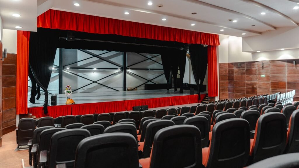 Theater stage with red curtains and rows of empty auditorium seats