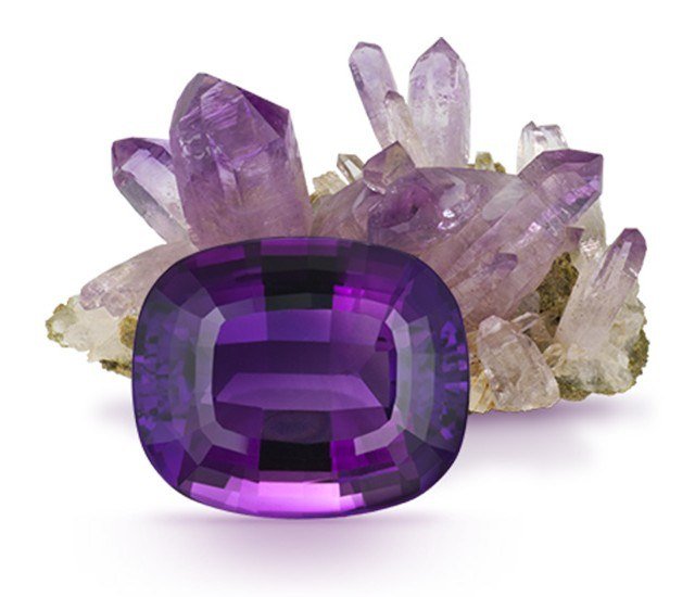Cushion-cut purple amethyst in front of a cluster of pale amethyst crystals