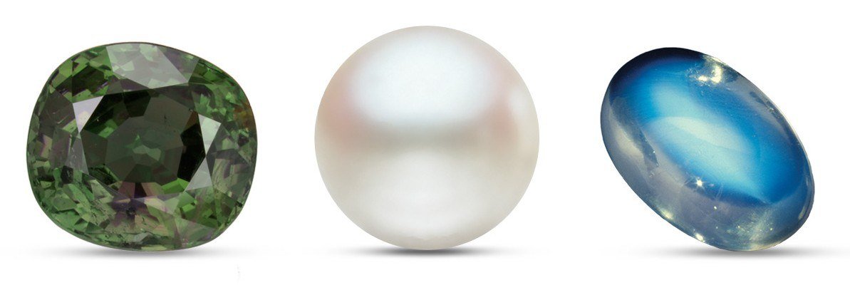 Green alexandrite, a white pearl and a blue-sheen moonstone cabochon side by side