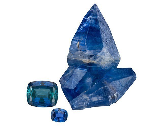 Rough blue sapphire crystal with two faceted blue sapphires