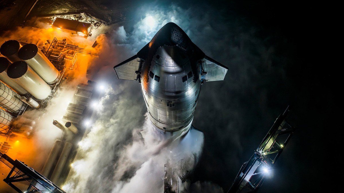 Starship upper stage seen from above on the pad at night with launch equipment lit orange