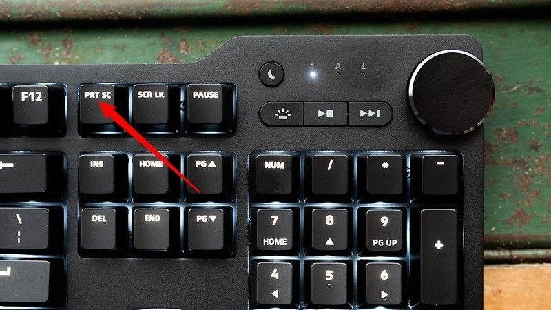 Red arrow pointing to the PRT SC key on a backlit desktop keyboard