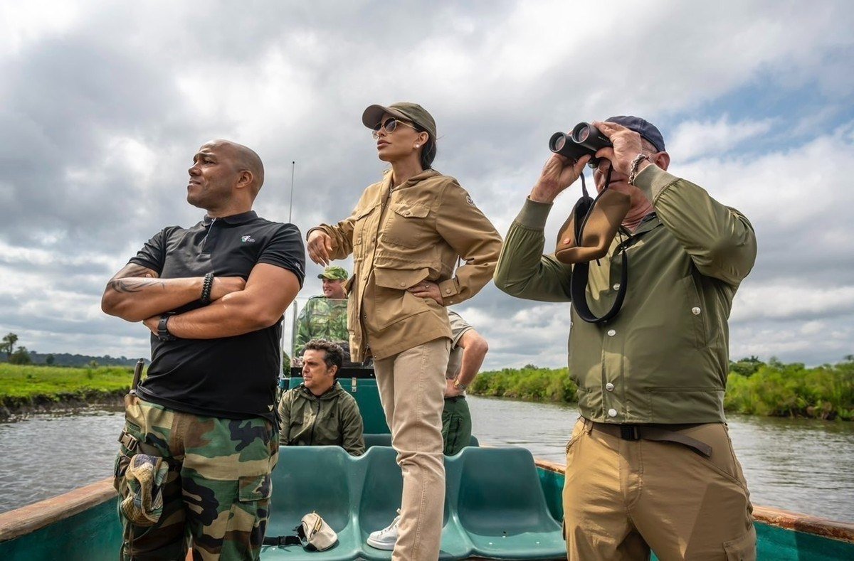 Three people on a boat scanning a river and wetland in Loango National Park, Gabon