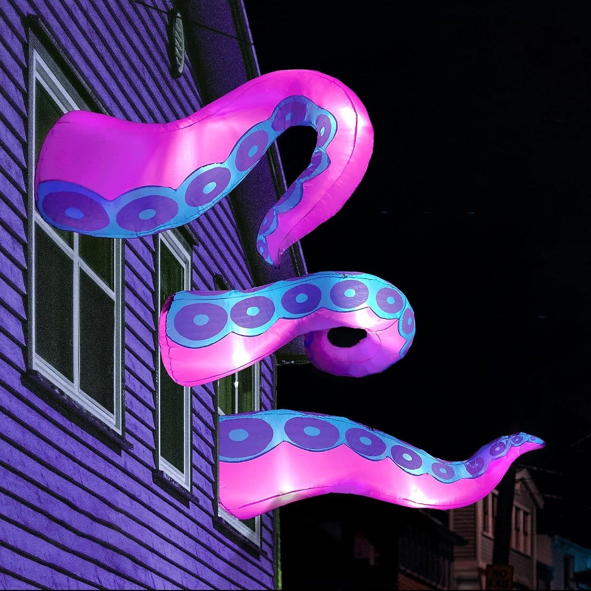 Three purple Joiedomi octopus tentacle inflatables reaching out of a house window