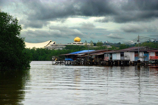 The golden-domed Istana Nurul Iman palace on the skyline beyond the stilt houses of Kampong Ayer on the Brunei River