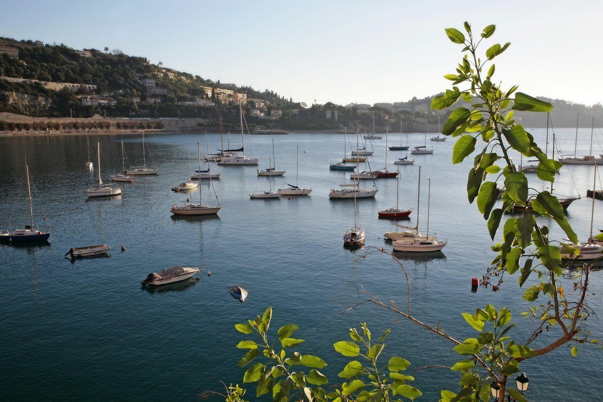 Yachts anchored in the bay of Villefranche-sur-Mer with the wooded Cap Ferrat headland behind