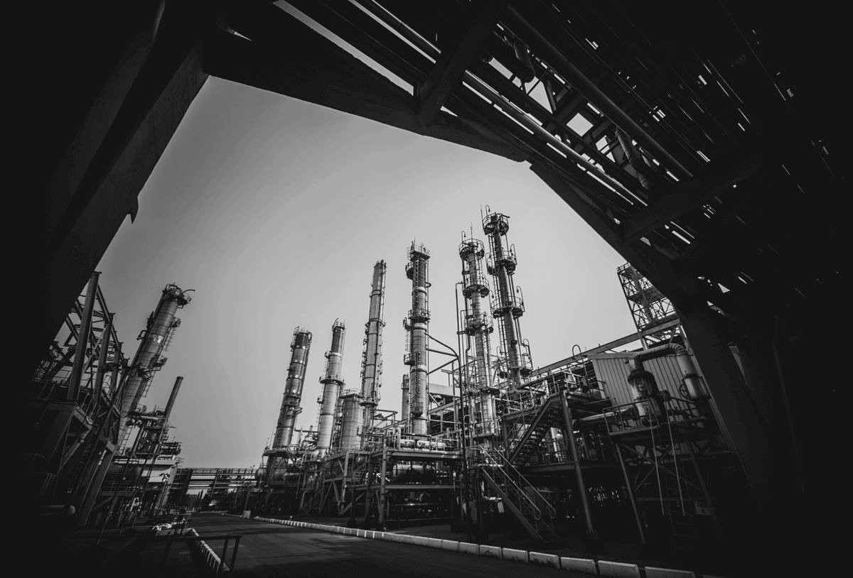 Black and white wide-angle photograph of refinery towers seen from below