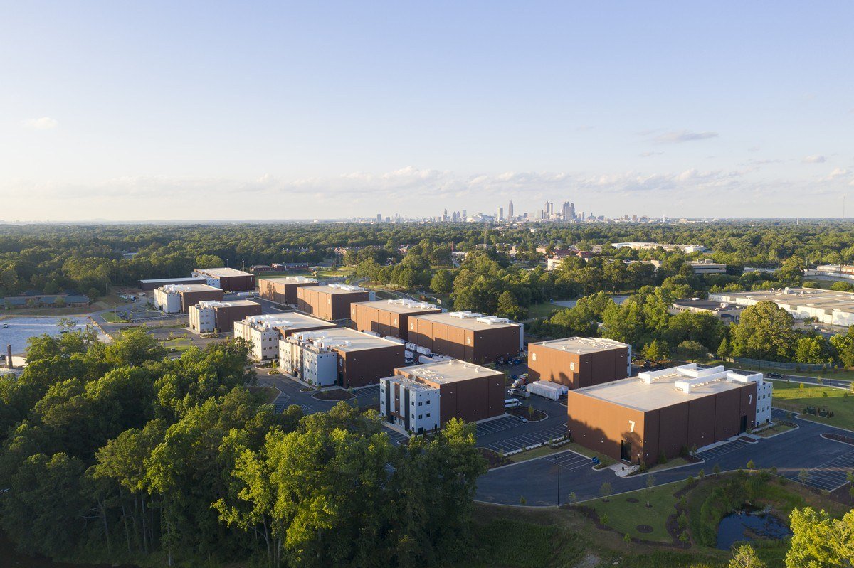 Aerial view of the Tyler Perry Studios sound stage buildings in Atlanta with the city skyline behind