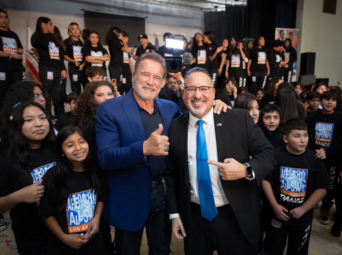 Arnold Schwarzenegger posing with a group of students at a USC Schwarzenegger Institute event