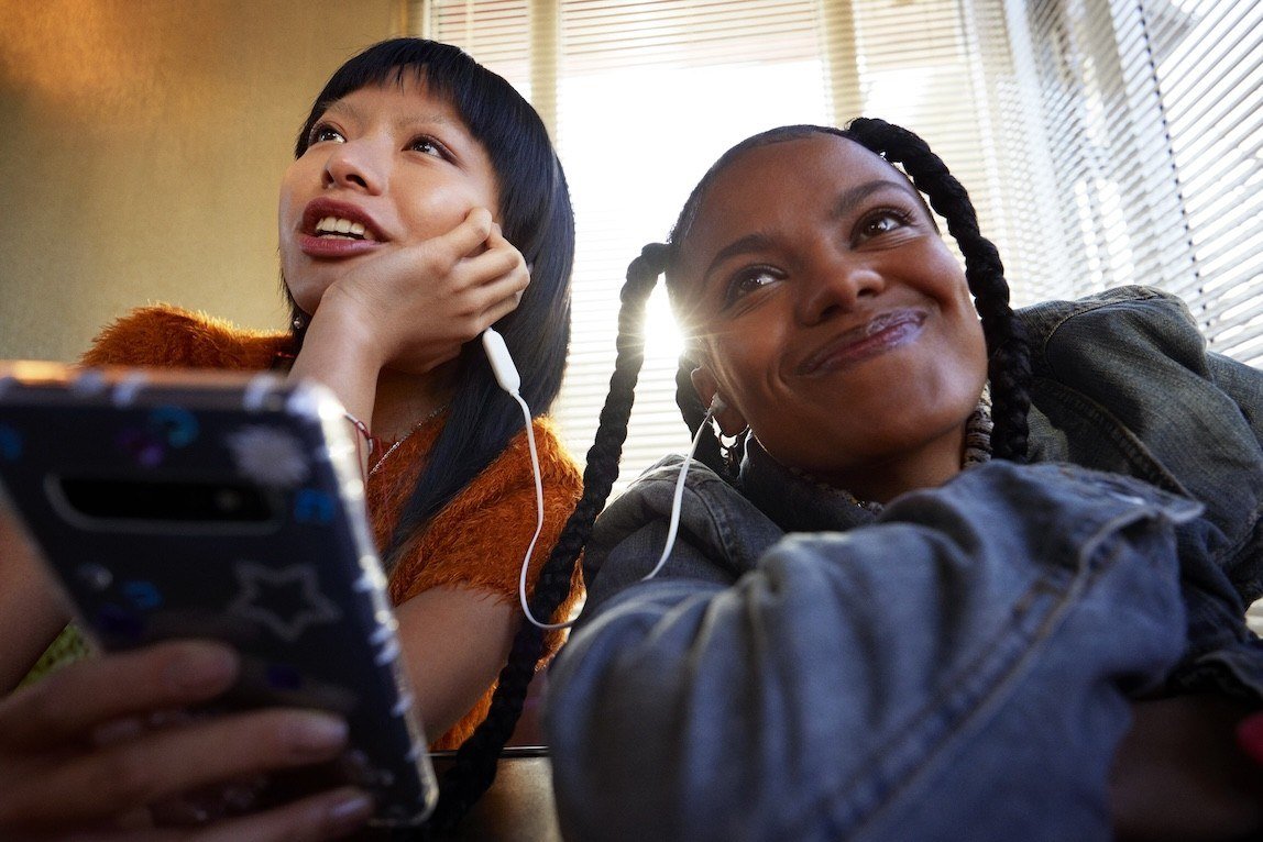 Two young people sharing earphones and a phone, from the Spotify press site