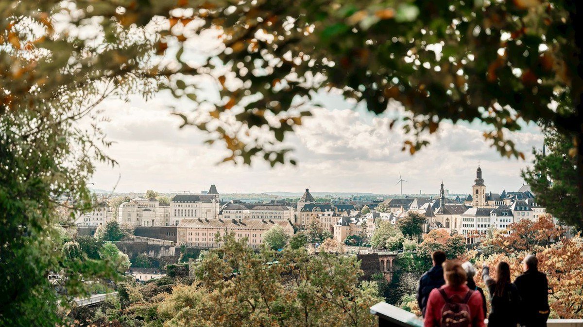 View over Luxembourg City rooftops from a hillside park with visitors in the foreground