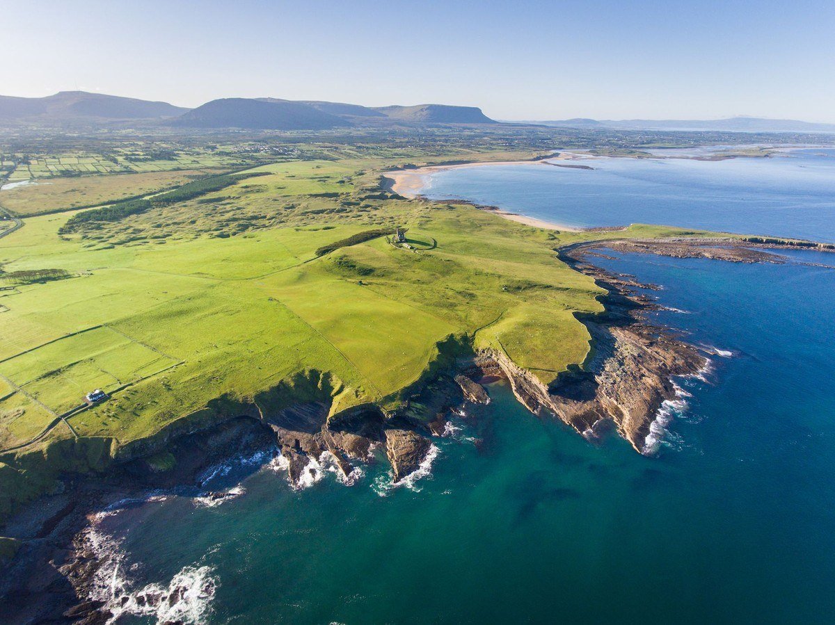 Aerial view of green coastal fields and a rocky shoreline in County Sligo
