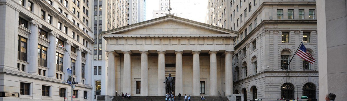 Columned facade of Federal Hall National Memorial between tall buildings
