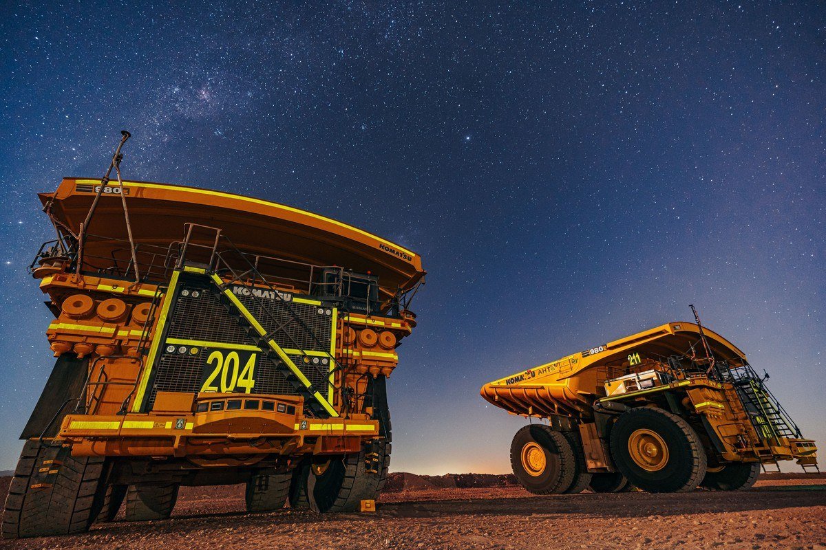 Two Antofagasta haul trucks parked under a starry night sky at a Chilean copper mine